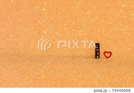 The inscription love is made of wooden letters and a red heart on a gold iridescent background. The inscription love is made of wooden letters and a red heart on a gold iridescent background. 74440008