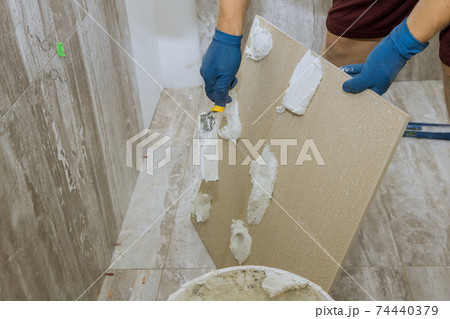 Spreading wet mortar before applying tiles on bathroom floor 74440379