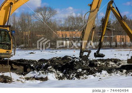 Excavator working on earthmoving at pit on winter backhoe digs, in the heavy construction equipment during excavation at construction Excavator working on earthmoving at pit on winter backhoe digs, in the heavy construction equipment during excavation at construction 74440494