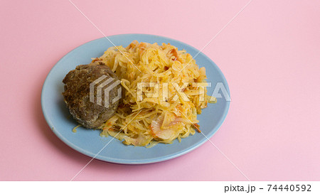 Stewed white cabbage with a cutlet steak on a plate. A dish of Russian, Polish cuisine. Garnish in the USSR. Stewed white cabbage with a cutlet steak on a plate. A dish of Russian, Polish cuisine. Garnish in the USSR. 74440592
