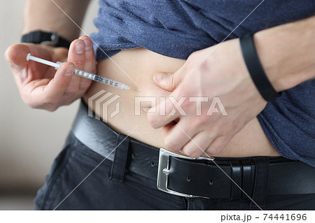 Man injects himself in stomach with an injection of insulin 74441696