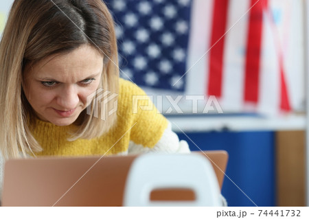 Woman works on computer in background hanging an American flag Woman works on computer in background hanging an American flag 74441732