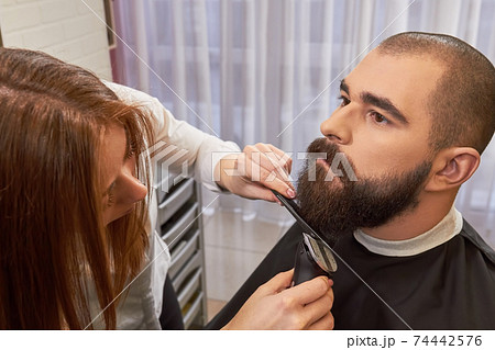 Barber woman grooming beard. 74442576