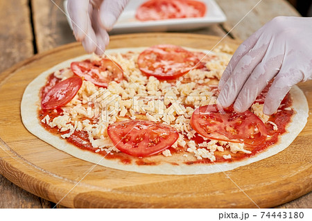 Adding tomatoes to pizza. 74443180