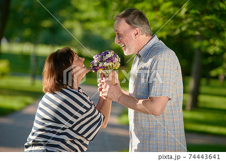 Happy mature couple holding flowers outdoors. Happy mature couple holding flowers outdoors. 74443641