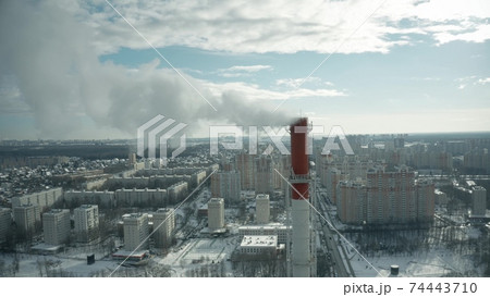 Aerial shot of a red and white smokestack in urban environment in winter 74443710