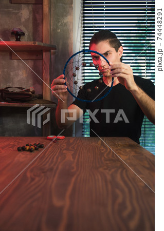 Artisan looks at dreamcatcher in authentic workshop. 74448291