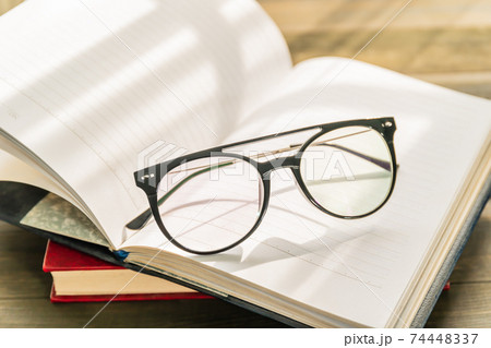 Reading glasses put on open book 74448337