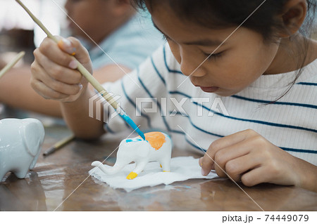 Close up asian child girl is concentrating to paint on small ceramic elephant with oil color. Kids arts and crafts creative activity class in school. Close up asian child girl is concentrating to paint on small ceramic elephant with oil color. Kids arts and crafts creative activity class in school. 74449079