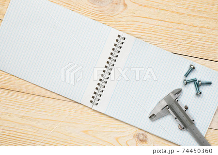 trammel and screw with empty notebook over wooden workbench trammel and screw with empty notebook over wooden workbench 74450360