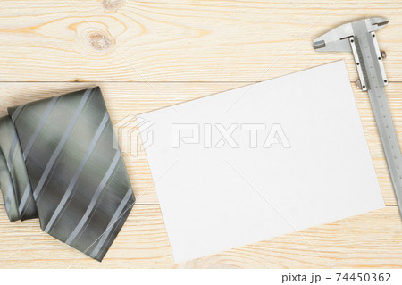 trammel and gray neck tie on workbench with empty paper sheet trammel and gray neck tie on workbench with empty paper sheet 74450362