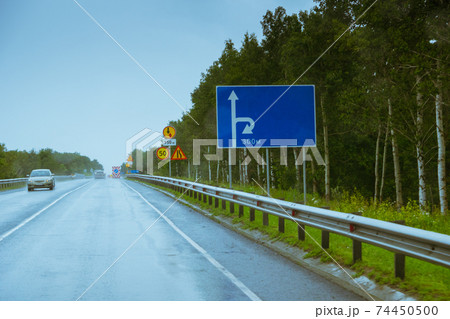 blank blue billboard with detour arrow directions and warning road signs near motorway 74450500