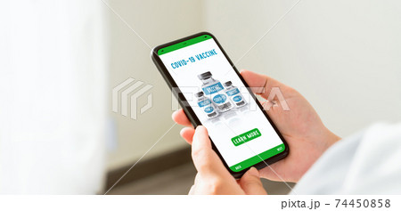 Hand holding smartphone and show web page corona vaccine online with learn more button. 74450858