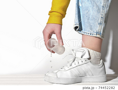 female hand pouring water on a white sneakers. female hand pouring water on a white sneakers. 74452282