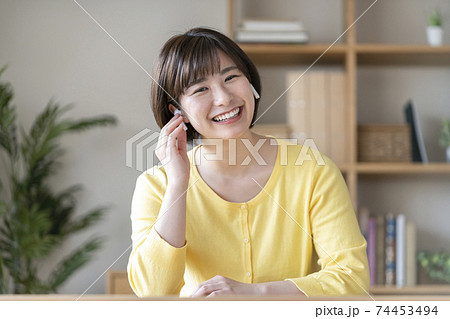 ワイヤレスヘッドホンをつけたカメラ目線の若い女性 74453494