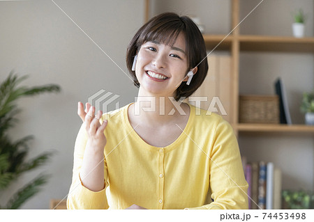 ワイヤレスヘッドホンをつけて話すカメラ目線の若い女性 74453498