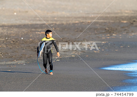 湘南の砂浜でサーフィンをし終わった小学生の男の子 74454799