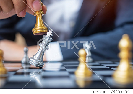 businessman hand moving gold Chess King figure and Checkmate opponent during chessboard competition. Strategy, Success, management, business planning, disruption and leadership concept 74455456