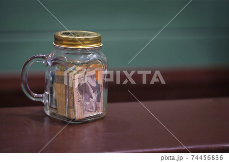 Tipping in a glass jar on a bar counter top 74456836