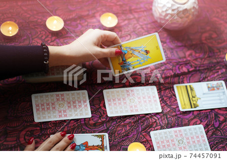 Tarot reader picking tarot cards near burning candles. Tarot reader picking tarot cards near burning candles. 74457091
