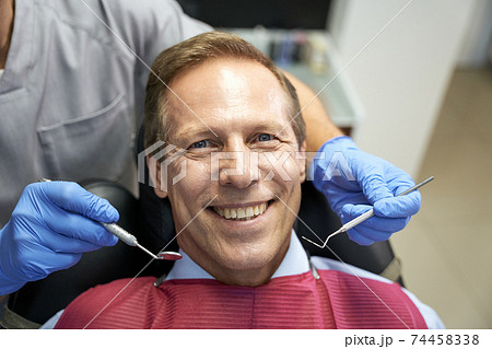 Optimistic man enjoying appointment at trusted dental clinic 74458338