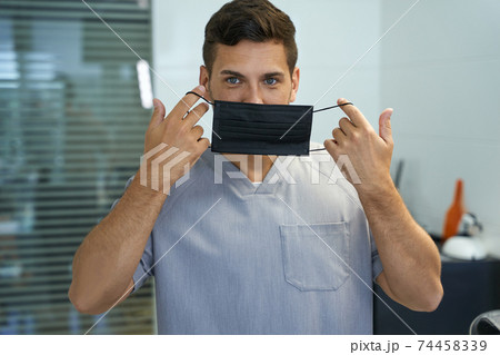 Handsome doctor demonstrating a way to put mask on 74458339