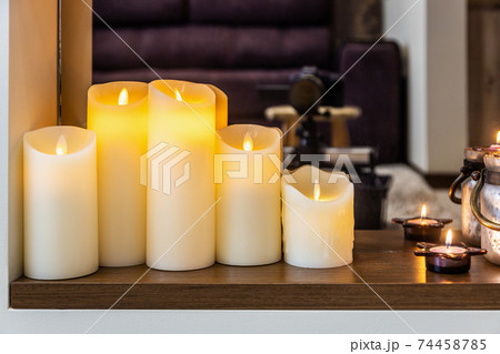 led electric and wax candles stand in the home fireplace 74458785