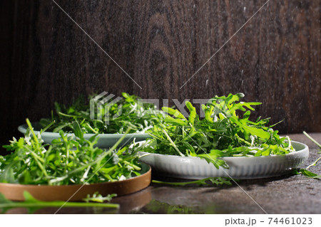 Fresh green raw leaves of arugula rucola salad on dark rustic wooden background. 74461023