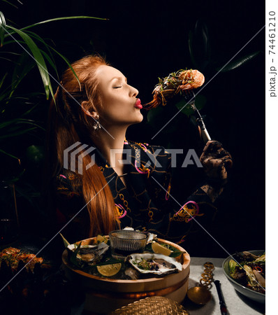 Rich red-haired woman is eating in seafood Rich red-haired woman is eating in seafood 74461210