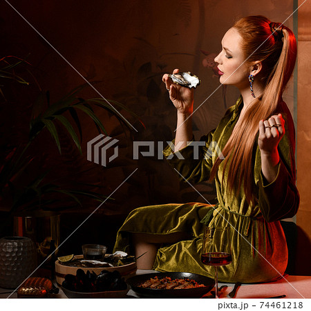 Rich red-haired woman is sitting on table laid Rich red-haired woman is sitting on table laid 74461218