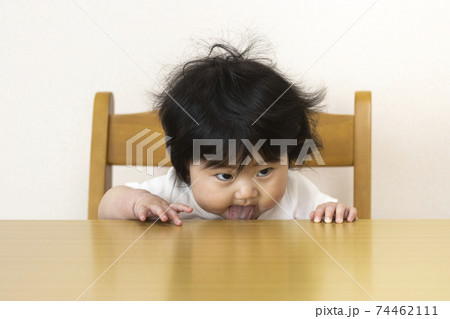 座って テーブルを舐める赤ちゃん 0歳 生後7か月 女の子 日本人 の写真素材