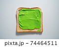 spreading Green paste on a toast on white Background. Top view 74464511