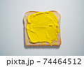 spreading Yellow paste on a toast on white Background. Top view 74464512
