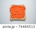 spreading Orange paste on a toast on white Background. Top view 74464513