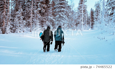 Two snowboarders are walking up the hill. View from the back. Extreme sports. Holidays in the mountains. WEB banner format shot. Back country Two snowboarders are walking up the hill. View from the back. Extreme sports. Holidays in the mountains. WEB banner format shot. Back country 74465522