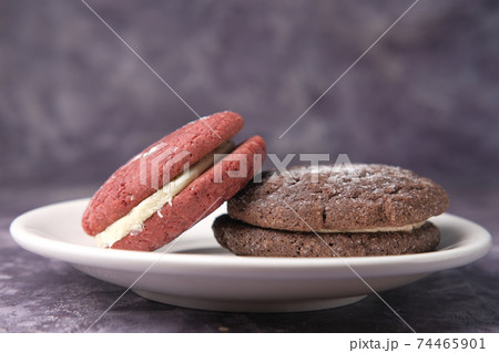 chocolate and red vanilla cookies on plate against black background  74465901