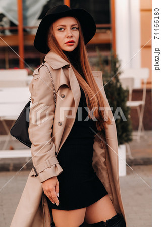 Stylish young woman in a beige coat in a black hat on a city street. Women's street fashion. Autumn clothing.Urban style 74466180