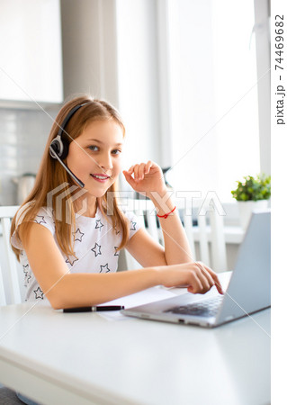 Teenager girl doing homework at home in front of a laptop monitor. She is looking at the camera and smiling. Teenager girl doing homework at home in front of a laptop monitor. She is looking at the camera and smiling. 74469682