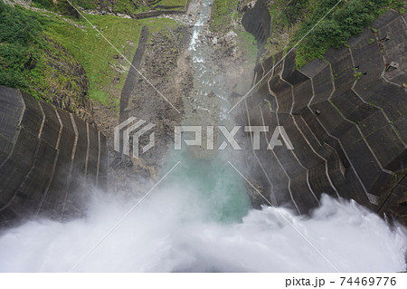 高所から川へ降り注ぐダムの水 74469776