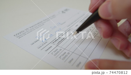 Filling COVID-19 Vaccination Record Card, 1st Dose COVID-19, close up view. 74470812
