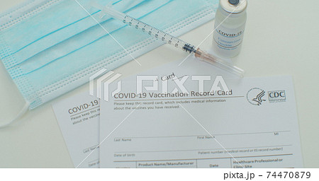 Medical mask and COVID-19 vaccine on vaccination record card approved by CDC with corona virus vaccine vials. White background. Medical mask and COVID-19 vaccine on vaccination record card approved by CDC with corona virus vaccine vials. White background. 74470879
