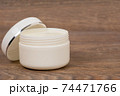 white opened plastic jar with body cream on wooden table 74471766