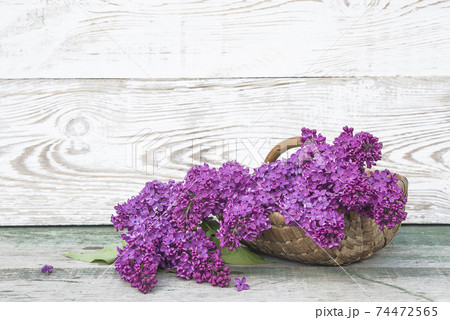 Happy Mothers's day greeting card. Bunch of purple lilacs in vintage wicker basket on rustic wooden background. Space for text 74472565
