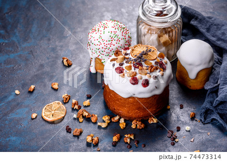 Festive cakes with white glaze, nuts and raisins with Easter eggs on the festive table Festive cakes with white glaze, nuts and raisins with Easter eggs on the festive table 74473314