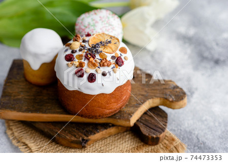 Festive cakes with white glaze, nuts and raisins with Easter eggs on the festive table 74473353