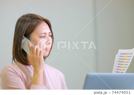 データを見ながらこれはまずいなあと思いながら電話するビジネスウーマン データを見ながらこれはまずいなあと思いながら電話するビジネスウーマン 74474051