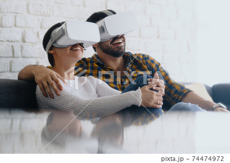 Young Couple Playing Virtual Reality With Headset On Sofa 74474972