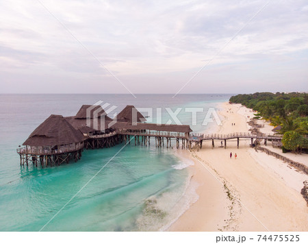 Top View on Beautiful thatch stilt house restaurant at Zanzibar Kendwa beach at evening time in Turquoise Water of Indian ocean Top View on Beautiful thatch stilt house restaurant at Zanzibar Kendwa beach at evening time in Turquoise Water of Indian ocean 74475525