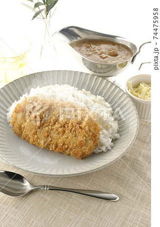 豚カツが乗った熱々ご飯とルーが入ったカレーポットとトッピングのナチュラルチーズとお茶とオリーブの葉 74475958