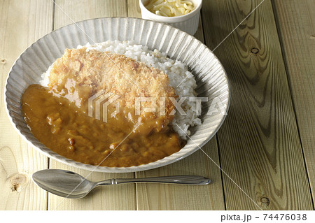 大きい豚カツが真ん中に一枚乗っている熱々カツカレーとトッピングのチーズとスプーン 74476038